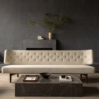 Elegant beige sofa with button detailing, paired with a sleek black marble coffee table on a warm wooden floor.