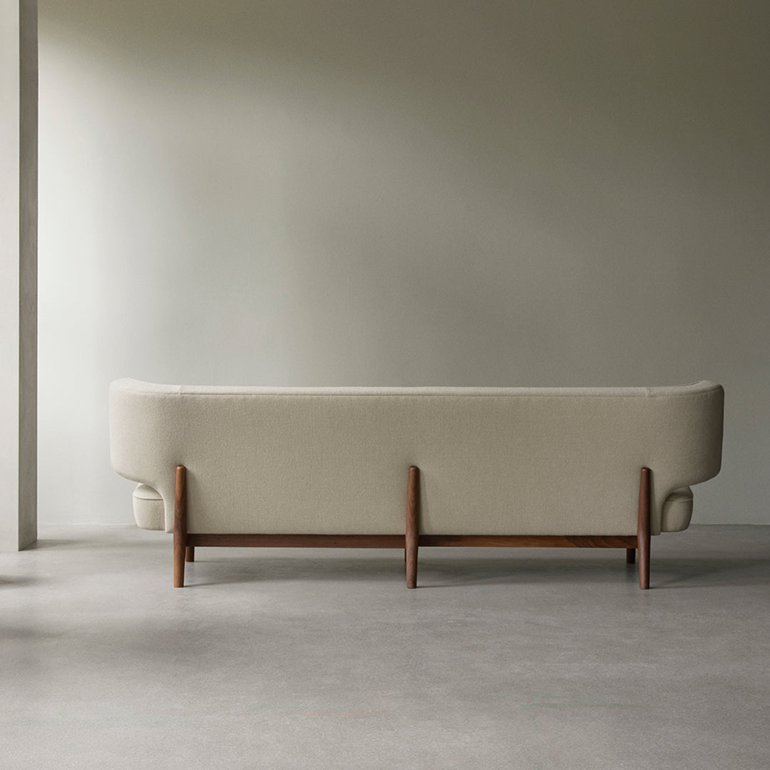 Minimalist light beige sofa with wooden legs, featuring a smooth texture and understated design accents.