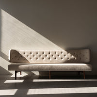 Beige tufted sofa with wooden legs, featuring a minimalist design and soft texture, set against a neutral backdrop.