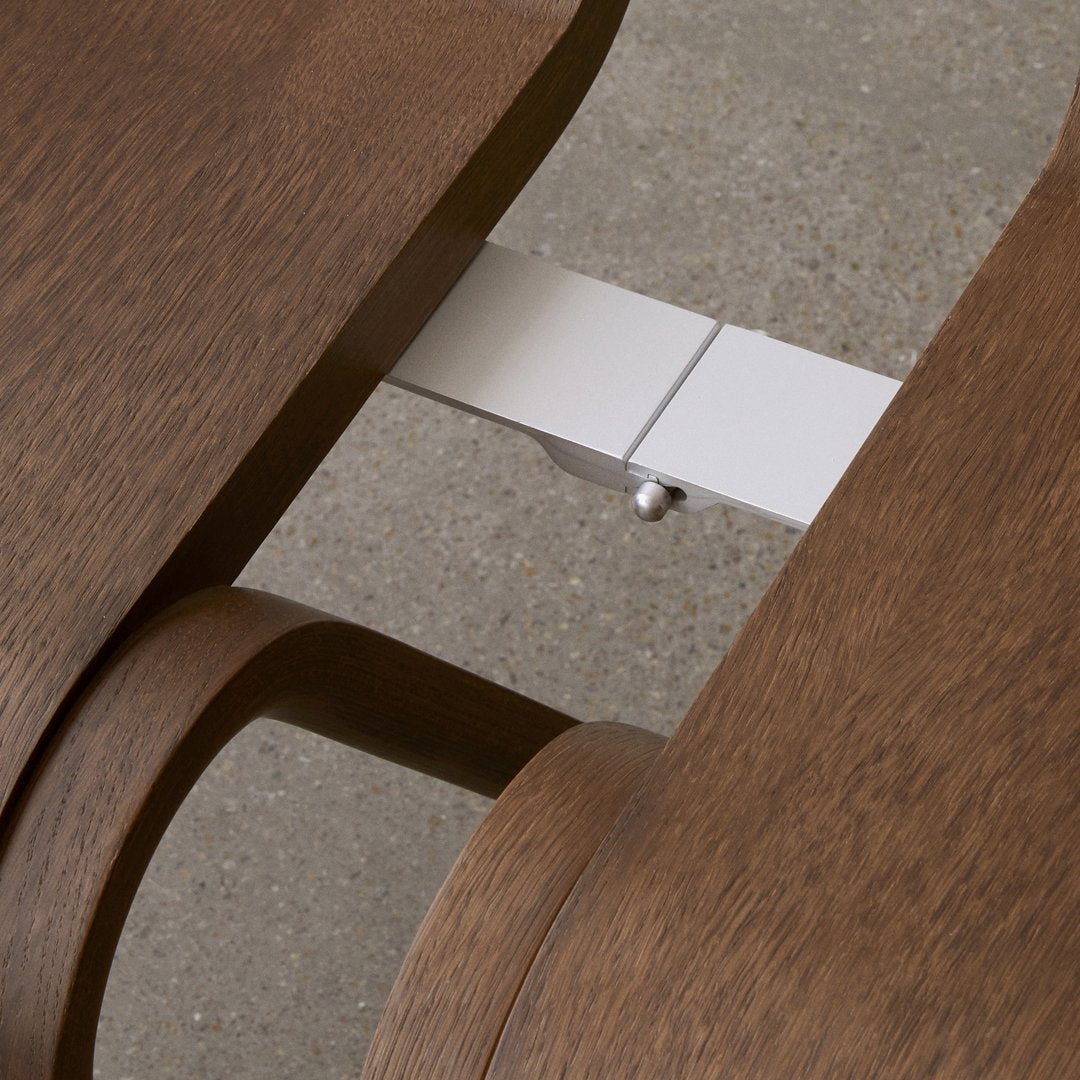 Close-up of smooth, rich brown wood grain with sleek silver metal connector, showcasing elegant, modern design.