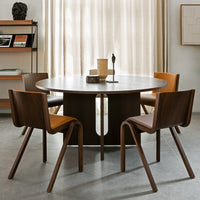 Round wooden dining table with contrasting dark and light wood chairs, featuring a minimalist design and warm tones.