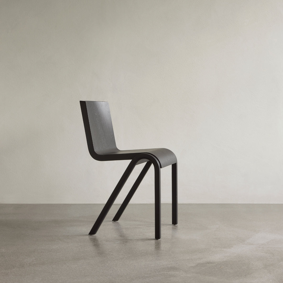 Sleek black chair with a minimalist design, featuring clean lines and smooth surfaces on a neutral background.