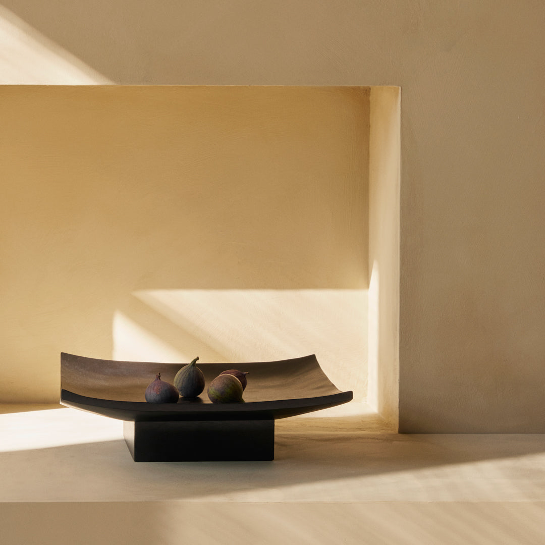 Stylish dark brown serving tray with subtle curves and a matte black base, set against a warm beige background.