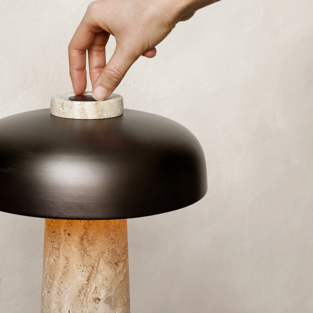Stylish black lamp with a beige stone base, showcasing elegant, minimalist design and warm light glow.