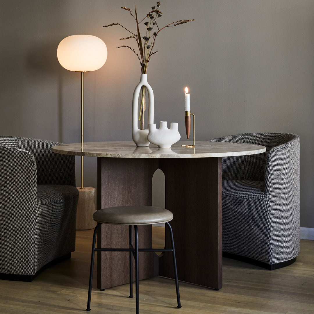 "Round marble table with wood base, paired with gray textured chairs, soft gray walls, and warm neutral decor elements."