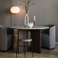 "Round marble table with wood base, paired with gray textured chairs, soft gray walls, and warm neutral decor elements."