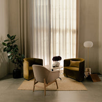 "Modern living room with olive and beige armchairs, light curtains, and a neutral rug, creating a cozy atmosphere."