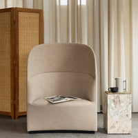 Beige curved armchair with a textured fabric, set against natural tones and subtle patterns in a contemporary interior.