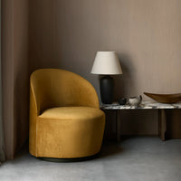 "Curved velvet chair in rich mustard yellow against a soft taupe wall and gray floor."