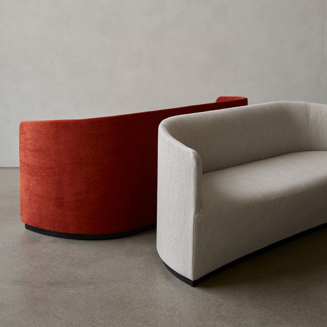 Curved sofa set featuring a rich terracotta and a soft gray fabric, paired with a sleek black base.