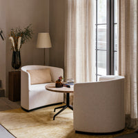 Modern cream armchairs with a soft texture, paired with a wooden table on a light beige rug and layered neutral curtains.
