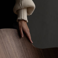 Cream ribbed sweater against a dark backdrop, with a rich wood surface, highlighting neutral and earthy tones.