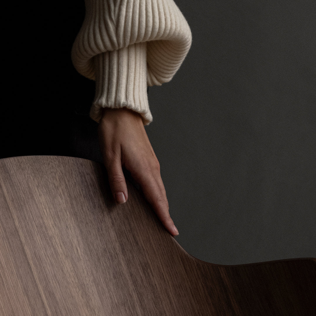 Ivory ribbed sweater with a warm wood tone and dark background, showcasing elegant textures and subtle contrasts.