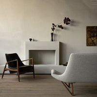 Modern living room featuring a black chair, gray upholstery, and earthy tones with a textured white wall.