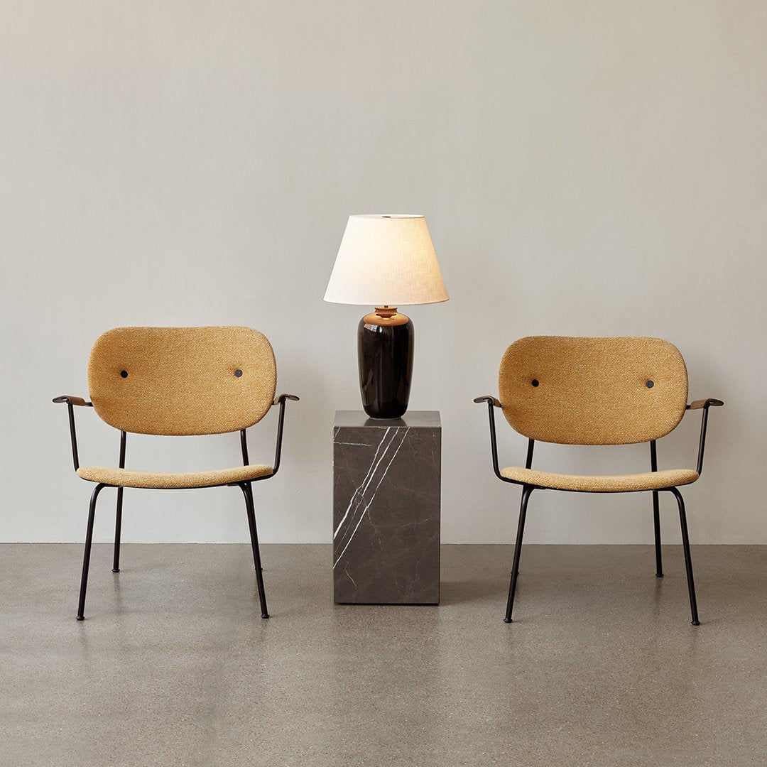 Natural beige chairs with black metal legs beside a dark marble lamp stand and soft white lampshade. Minimalist design.
