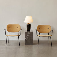 Natural beige chairs with black metal legs beside a dark marble lamp stand and soft white lampshade. Minimalist design.
