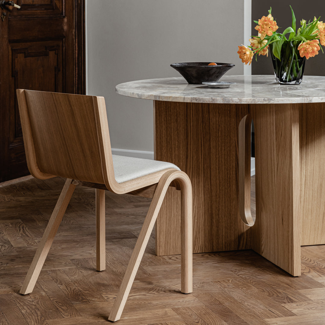 Natural wood chair with a light finish, paired with a sleek marble-top table in a modern, neutral-toned setting.