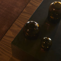 "Amber glass vases on a dark wooden surface with a rich textural contrast to the warm brown background."