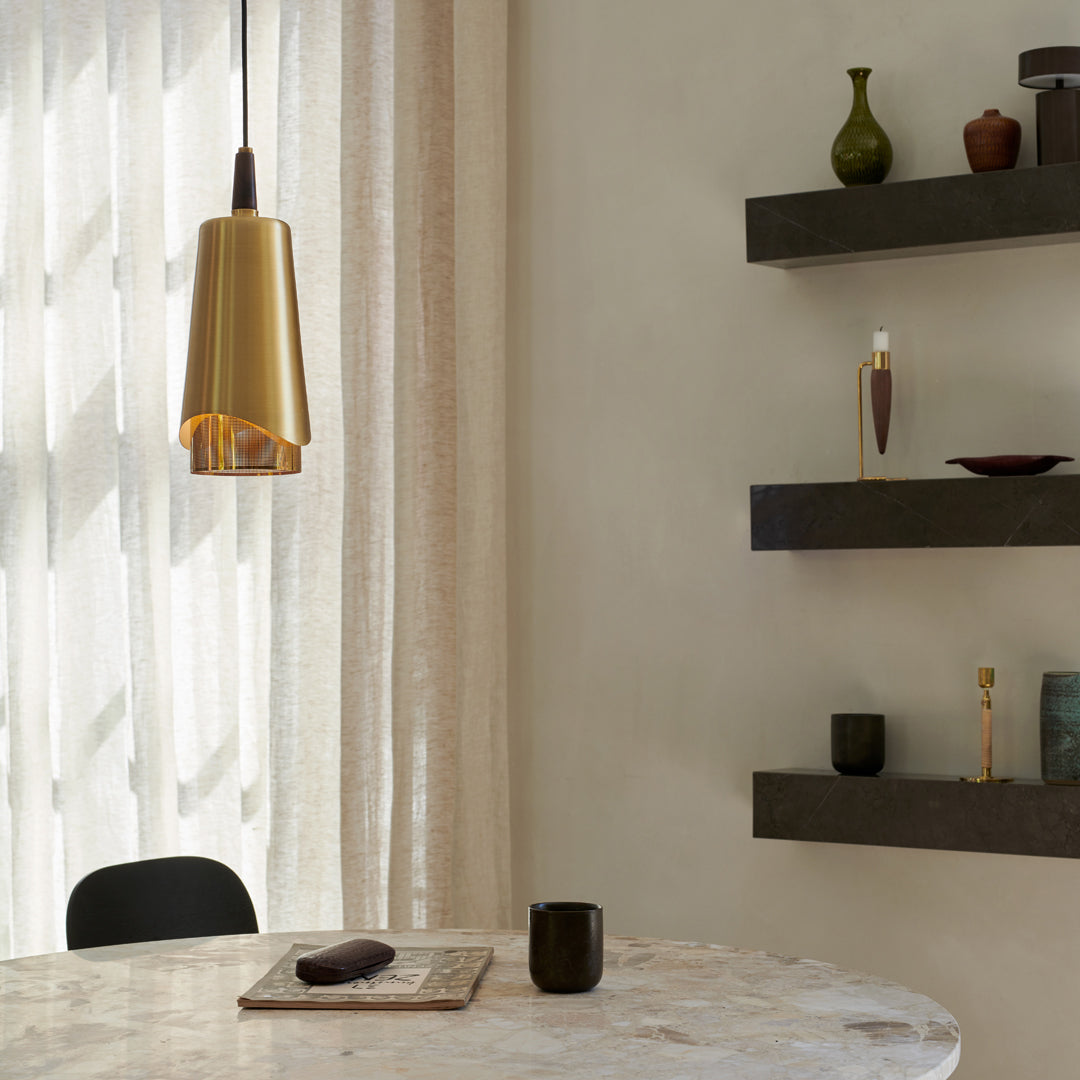 Gold pendant light against soft beige walls, featuring smooth surfaces and minimalist black shelves with earthy accents.