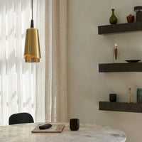 Gold pendant light against soft beige walls, featuring smooth surfaces and minimalist black shelves with earthy accents.