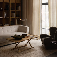 Neutral-toned living room with a beige sofa, soft gray armchair, and light wood coffee table on a textured rug.