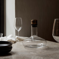 Clear glass decanter with a gold and black accent, paired with elegant glassware on a light marble surface.