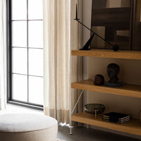 "Sheer beige curtains with subtle texture, natural wood shelves, and black accents for a modern aesthetic."