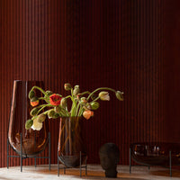 Amber glass vases with colorful floral arrangements against a rich brown background and sleek black accents.
