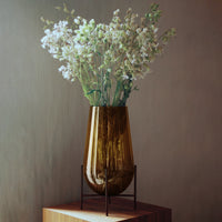 Amber glass vase with textured surface, accented by delicate white floral arrangement. Elegant and modern home décor.