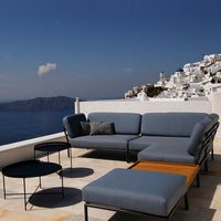 Modern outdoor lounge set featuring soft blue cushions, sleek black metal frames, and a warm wood accent table.