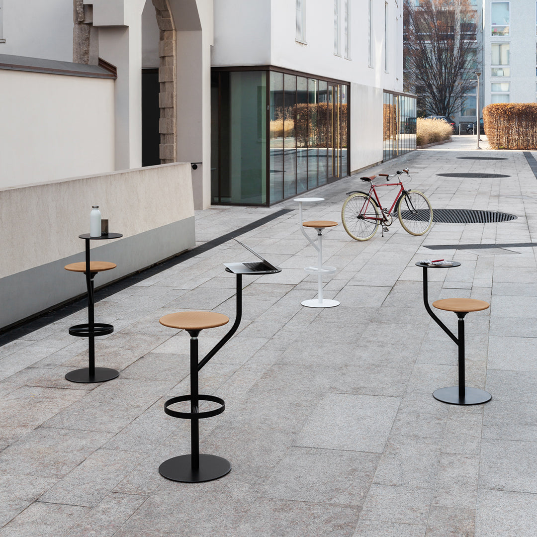 Modern outdoor barstools with natural wood seats and sleek black and white metal bases, set on a textured stone patio.