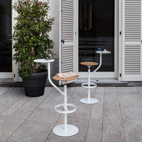 Modern white bar tables with circular bases and wooden tops, featuring sleek lines and a stylish outdoor setting.