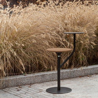 Stylish black and wood bar stool with a modern design, set against a backdrop of tall golden grasses.