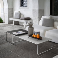 Modern coffee tables in black and white with minimalist design, set against a neutral stone floor.