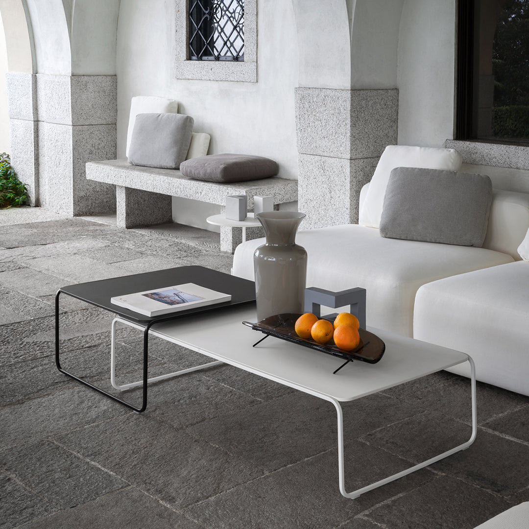 Modern black and white coffee tables with minimalist design, set on a textured stone patio.