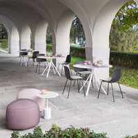 Cozy outdoor seating with soft pink and gray tones, featuring minimalist patterns on tables and cushions.