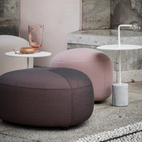 "Soft pink and gray ottomans with smooth textures alongside a minimalist white and marble table."
