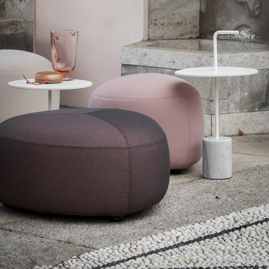 Soft pink and dark gray ottomans with a subtle two-tone pattern, paired with minimalist white and marble side tables.