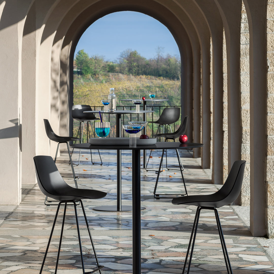 "Modern black chairs with sleek lines, set against a patterned stone floor, creating a stylish outdoor dining space."