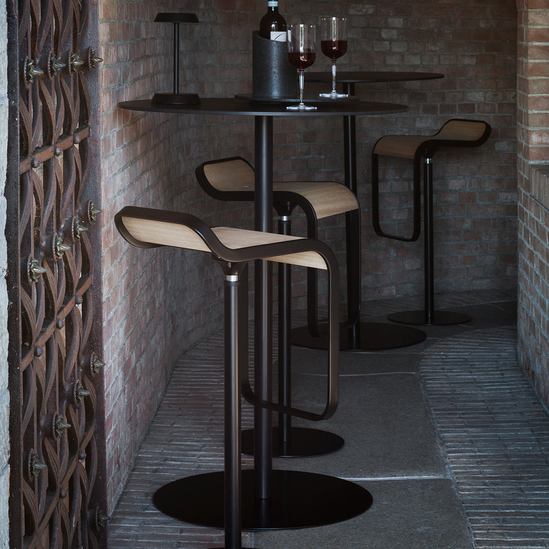 Stylish black bar stools with beige seat cushions against a rustic brick backdrop, creating a modern yet cozy vibe.