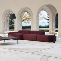 Modern burgundy modular sofa with smooth, rounded shapes, set against a minimalistic, neutral-toned interior.