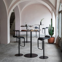 Modern bar furniture set featuring sleek black chairs and tables against a soft pink archway backdrop.