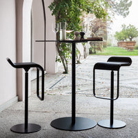 Modern black bar table and stools with sleek lines, set against a natural backdrop. Ideal for stylish spaces.