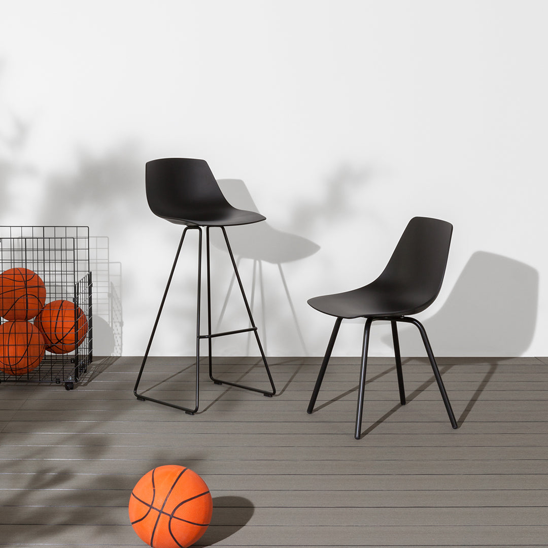 "Stylish black bar stools with sleek curves, set against a minimal white backdrop and vibrant orange basketballs."