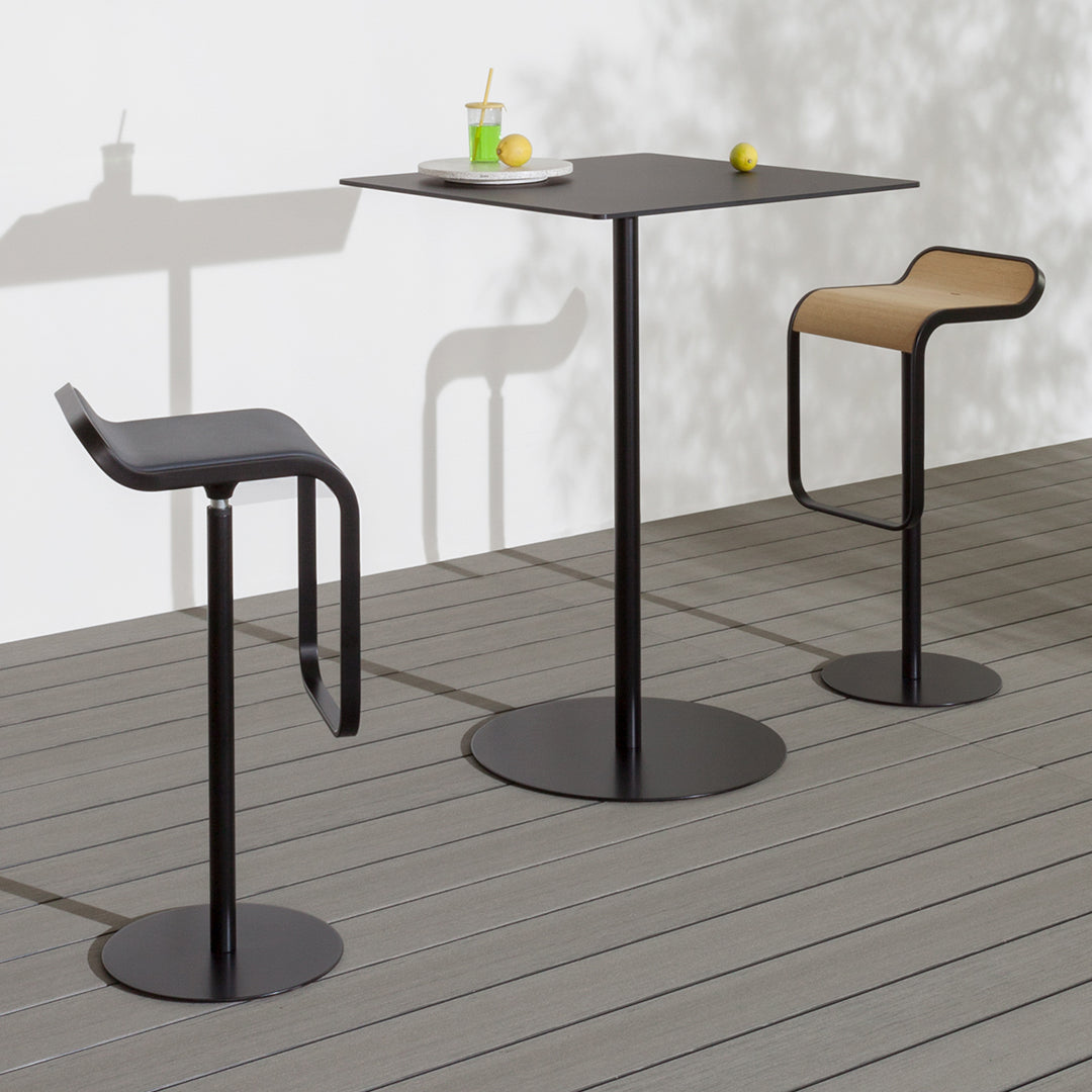 Modern black bar table and stools with beige seating, featuring clean lines and a minimalist design on a wooden deck.