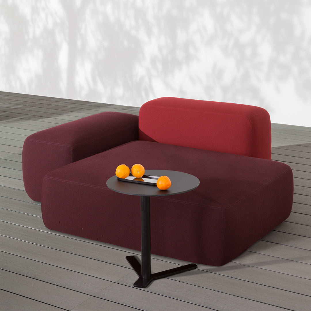 Burgundy and deep red sectional sofa with smooth, modern lines and a minimalist black side table.