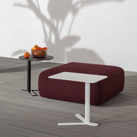 "Contemporary furniture set featuring a white table and black side table against a rich burgundy pouf."