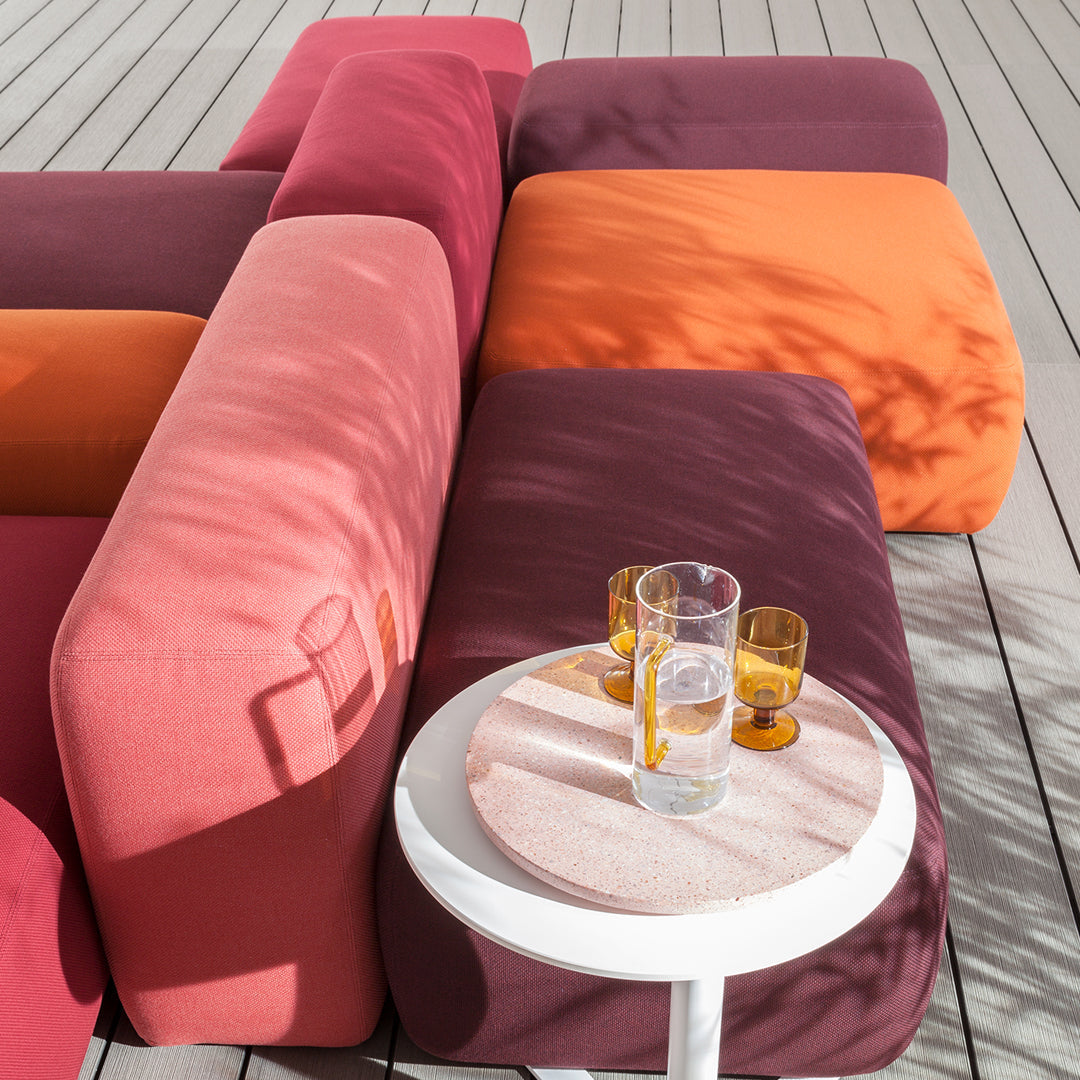 Colorful outdoor seating featuring pink, orange, and deep purple cushions with a modern design and circular table.