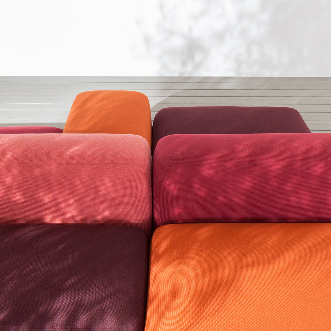 Vibrant cushions in shades of orange, pink, and deep burgundy with a smooth texture and soft shadows.