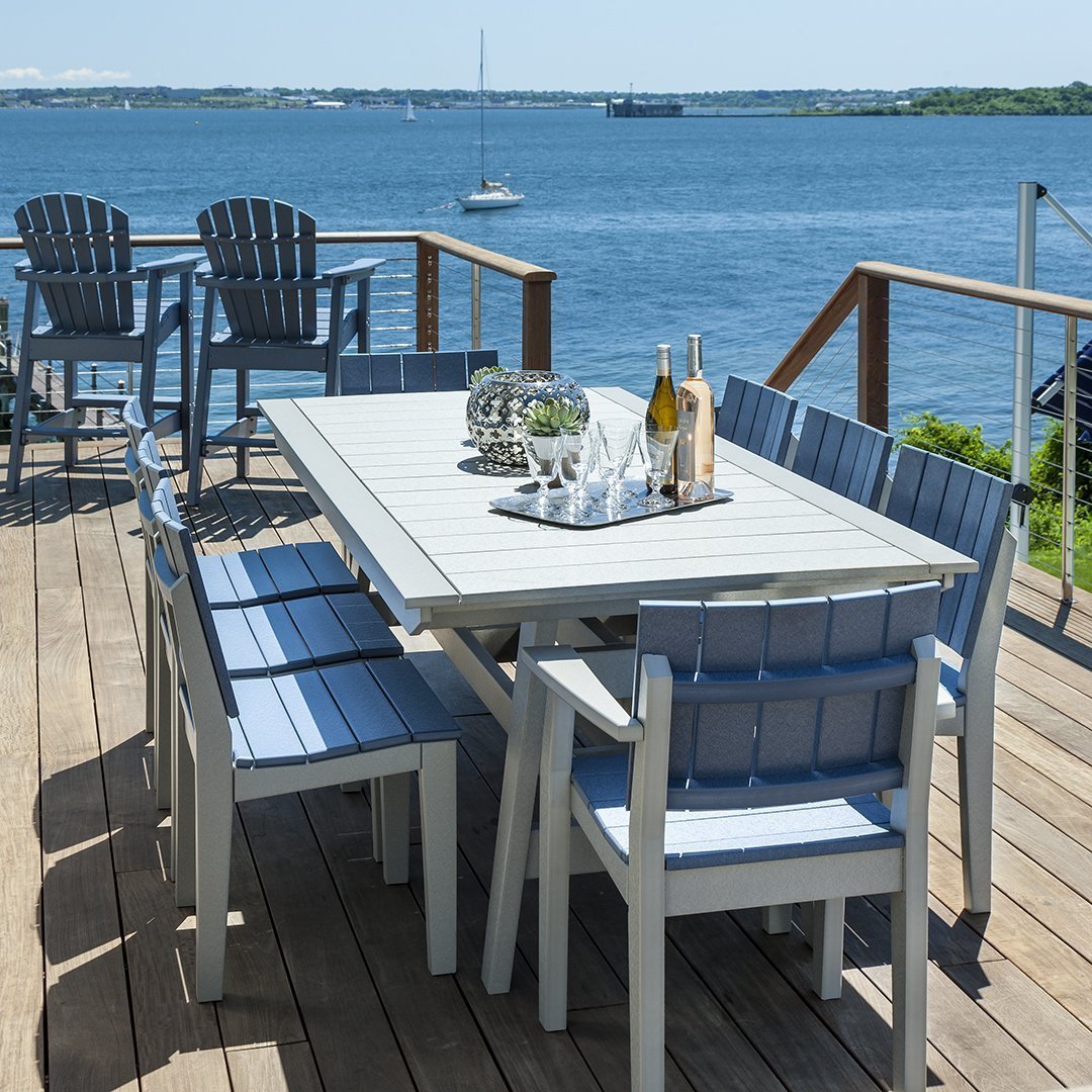 "Stylish outdoor dining set in soft gray and blue hues, set against a scenic waterfront backdrop."
